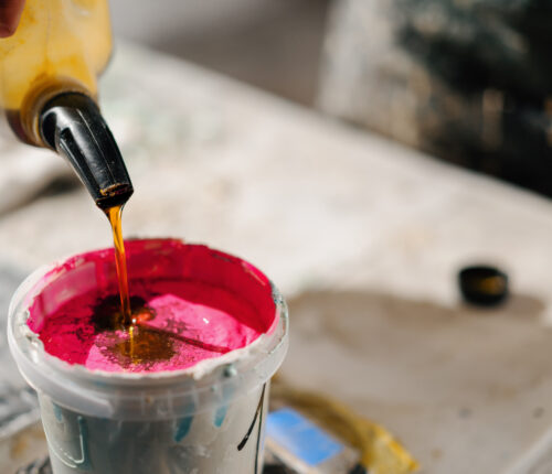 Artisan sculptor artist mixing paint in his workshop. Pink paint, paint mixer