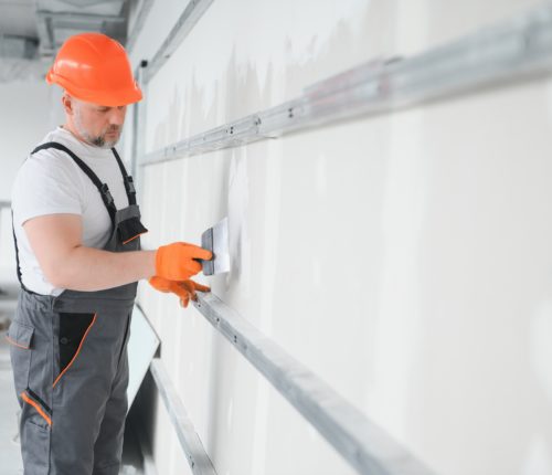 apartment interior construction - worker plastering gypsum board wall
